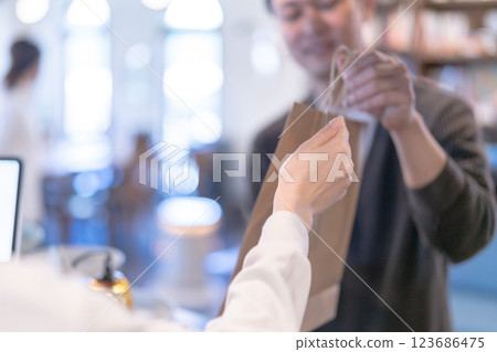 Smiling restaurant employee handing over a product, no face 123686475