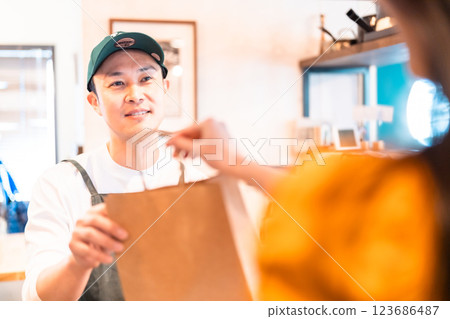 A smiling restaurant clerk handing over the product A smiling restaurant clerk handing over the product 123686487