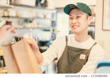 A smiling restaurant clerk handing over the product A smiling restaurant clerk handing over the product 123686489