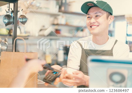 微笑的男性工作人員和女顧客處理智慧型手機付款 123686497