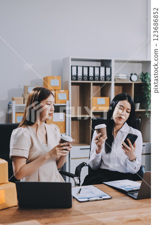 Startup SME small business entrepreneur of freelance Asian woman using a laptop with box Cheerful success Asian woman her hand lifts up online marketing packaging box and delivery SME idea concept 123686852