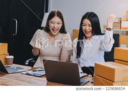 Startup SME small business entrepreneur of freelance Asian woman using a laptop with box Cheerful success Asian woman her hand lifts up online marketing packaging box and delivery SME idea concept Startup SME small business entrepreneur of freelance Asian woman using a laptop with box Cheerful success Asian woman her hand lifts up online marketing packaging box and delivery SME idea concept 123686854