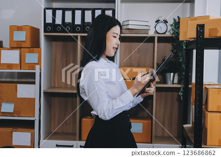 Startup SME small business entrepreneur of freelance Asian woman using a laptop with box Cheerful success Asian woman her hand lifts up online marketing packaging box and delivery SME idea concept 123686862