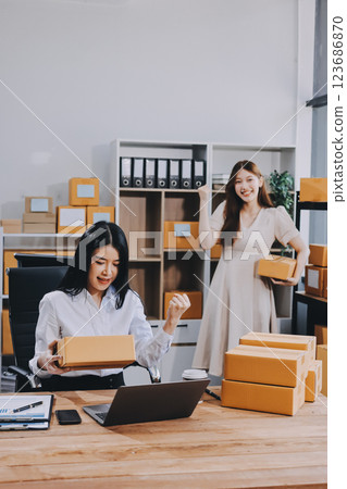 Asian SME business women use laptop computer checking customer order online shipping boxes at home. Starting Small business entrepreneur SME freelance. Online business, Work at home concept. Asian SME business women use laptop computer checking customer order online shipping boxes at home. Starting Small business entrepreneur SME freelance. Online business, Work at home concept. 123686870