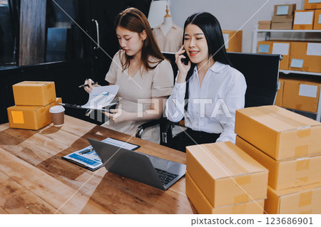 Startup SME small business entrepreneur of freelance Asian woman using a laptop with box Cheerful success Asian woman her hand lifts up online marketing packaging box and delivery SME idea concept Startup SME small business entrepreneur of freelance Asian woman using a laptop with box Cheerful success Asian woman her hand lifts up online marketing packaging box and delivery SME idea concept 123686901