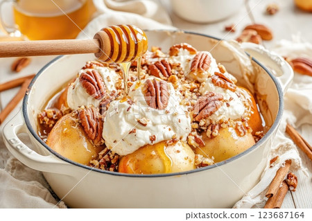 Delicious baked apples topped with whipped cream, honey, pecans, and cinnamon in a cozy kitchen setting 123687164