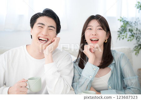 Smiling young couple in the living room, looking at the camera, laughing and looking happy Smiling young couple in the living room, looking at the camera, laughing and looking happy 123687323