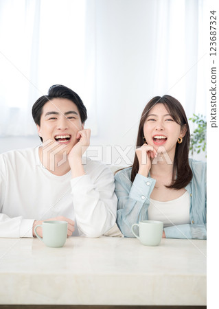 客廳裡微笑的年輕夫婦,看著鏡頭,笑著,看起來很開心 客廳裡微笑的年輕夫婦,看著鏡頭,笑著,看起來很開心 123687324