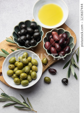 Variety of olives, olive oil, and olive branches served on a wooden board 123687444