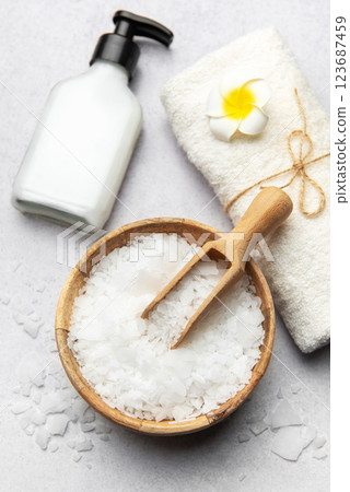 Magnesium flakes in bowl with scoop, towel, and dispenser on grey table for spa treatment 123687459