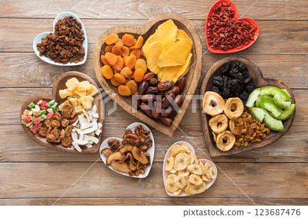 Healthy sweet dried fruits and berries in wooden heart shaped plates on wooden background.Top view. 123687476