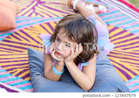 Adorable toddler girl is on the bright mat outdoors in the garden. 123687679