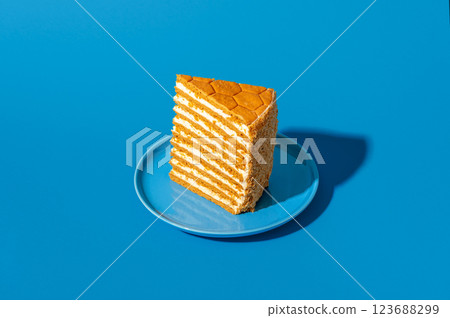 Slice of medovik, honey layered cake, isolated on a blue background Slice of medovik, honey layered cake, isolated on a blue background 123688299