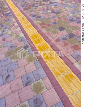 A view of a stone-paved road with tactile paving starting to dry after an early spring rain A view of a stone-paved road with tactile paving starting to dry after an early spring rain 123689121