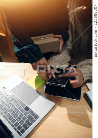 Startup small business SME, Entrepreneur owner African woman using smartphone or tablet taking receive and checking online purchase shopping order to preparing pack product box. 123689307