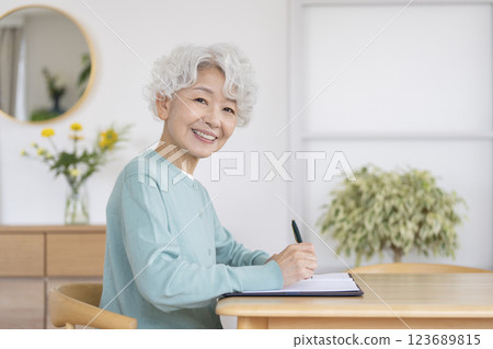 微笑的老年婦女拿著筆，看著相機 123689815