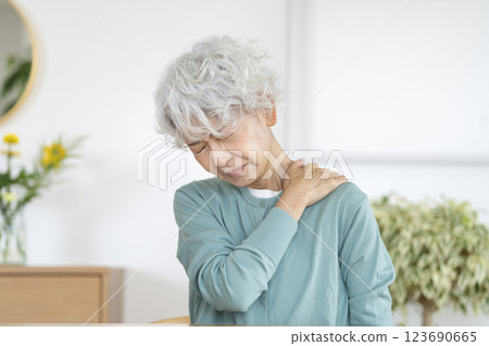 A senior woman with a painful expression holding her shoulder 123690665