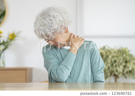 A senior woman with a painful expression holding her shoulder A senior woman with a painful expression holding her shoulder 123690781