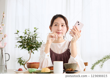 一位女士在吃早餐時看著她的智慧型手機 一位女士在吃早餐時看著她的智慧型手機 123690815