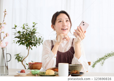 一位女士在吃早餐時看著她的智慧型手機 一位女士在吃早餐時看著她的智慧型手機 123690816