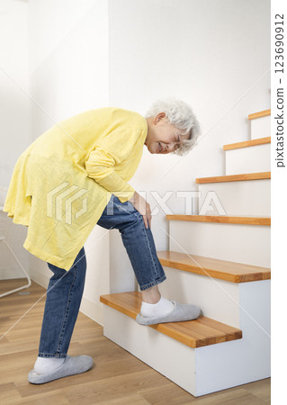 老年婦女抱著膝蓋爬樓梯 老年婦女抱著膝蓋爬樓梯 123690912