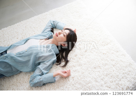 Aerial view of a young woman relaxing lying on her back in a room Aerial view of a young woman relaxing lying on her back in a room 123691774