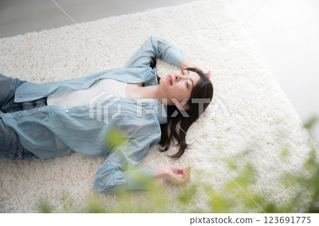 Wide-angle overhead view of a young woman relaxing lying on her back in a room 123691775