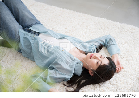 Aerial view of a relaxing young woman lying on her back in a room with her eyes closed, relaxing or taking a nap, wide angle 123691776
