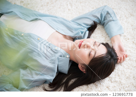 Aerial view of a young woman relaxing lying on her back in a room 123691778