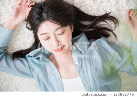 Aerial view of a young woman relaxing lying on her back in a room Aerial view of a young woman relaxing lying on her back in a room 123691779