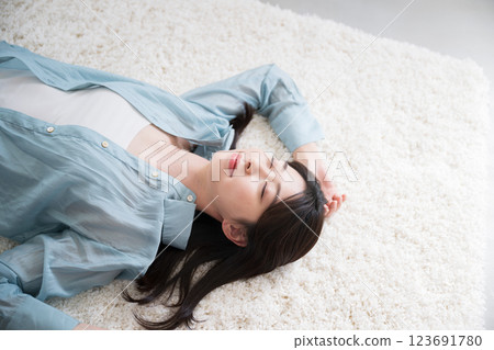 Aerial view of a young woman relaxing lying on her back in a room 123691780