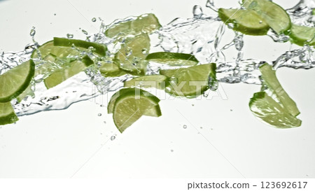 Fresh lime slices falling in water splashes, isolated on white background. Fresh lime slices falling in water splashes, isolated on white background. 123692617