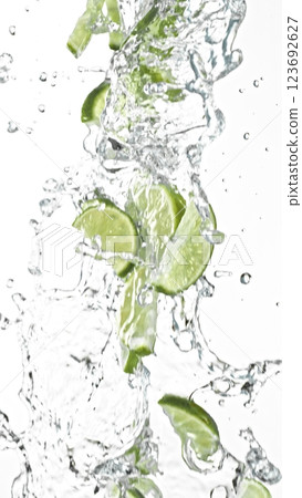 Fresh limes slices falling in water splashes, isolated on white background. 123692627