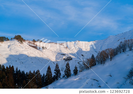 Snow-capped mountains and coniferous forests against the blue winter sky Snow-capped mountains and coniferous forests against the blue winter sky 123692728