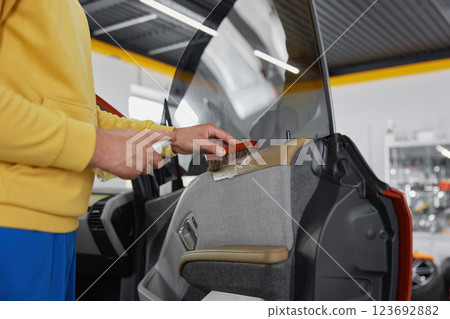 Man brushing leather parts of car door during auto detailing procedure 123692882