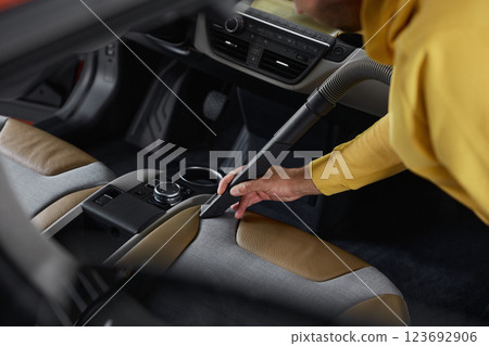 Car service worker cleaning front seats from dust and dirt using vacuum cleaner 123692906