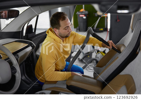 Male master vacuuming car interior from dust using professional equipment 123692926
