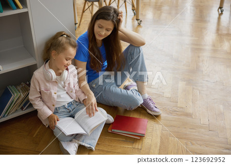 Happy mother and daughter spending time together in library or bookstore Happy mother and daughter spending time together in library or bookstore 123692952
