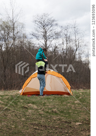 Two adventurers celebrate nature under a dramatic sky with vibrant tent as child joyfully experiences the thrill of the outdoors while being lifted by a caregiver Two adventurers celebrate nature under a dramatic sky with vibrant tent as child joyfully experiences the thrill of the outdoors while being lifted by a caregiver 123693096
