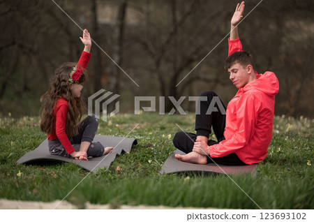 Joyful yoga practice in a serene green park with a child and adult sharing laughter and connection during a warm afternoon in nature Joyful yoga practice in a serene green park with a child and adult sharing laughter and connection during a warm afternoon in nature 123693102
