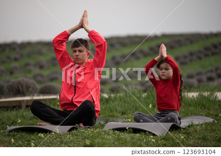 Practice mindfulness and focus in a serene lavender field with children, showcasing a connection to nature during a calm afternoon yoga session 123693104