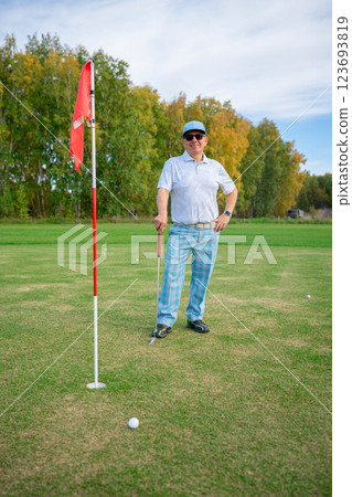 A Fashionable Golfer is Posing Confidently on the Beautiful Green Grass in Trendy Athletic Attire A Fashionable Golfer is Posing Confidently on the Beautiful Green Grass in Trendy Athletic Attire 123693819
