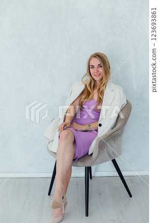 Beautiful blonde woman sitting on a chair in purple summer dress 123693861