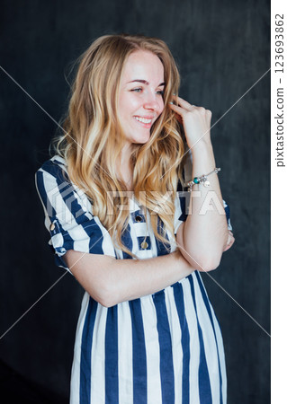 Beautiful fashionable woman in summer striped dress smiling Beautiful fashionable woman in summer striped dress smiling 123693862