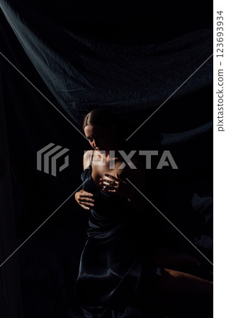 Beautiful slender woman in summer silk dress on black background Beautiful slender woman in summer silk dress on black background 123693934
