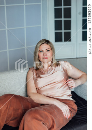 Woman in home clothes sitting on sofa in white room interior Woman in home clothes sitting on sofa in white room interior 123693969