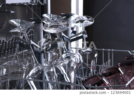 Wine glasses in dishwasher. Clean and tidy. Organizing dishes on holder, loading dirty items. Wine glasses in dishwasher. Clean and tidy. Organizing dishes on holder, loading dirty items. 123694001