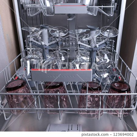 Wine glasses in dishwasher. Clean and tidy. Organizing dishes on holder, loading dirty items. Wine glasses in dishwasher. Clean and tidy. Organizing dishes on holder, loading dirty items. 123694002