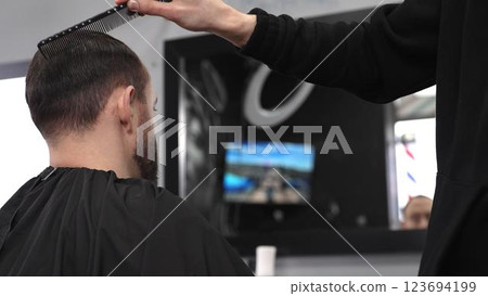 Professional hairdresser styling male client's hair, mirror reflecting classic barber pole, salon interior with modern grooming ambiance Professional hairdresser styling male client's hair, mirror reflecting classic barber pole, salon interior with modern grooming ambiance 123694199