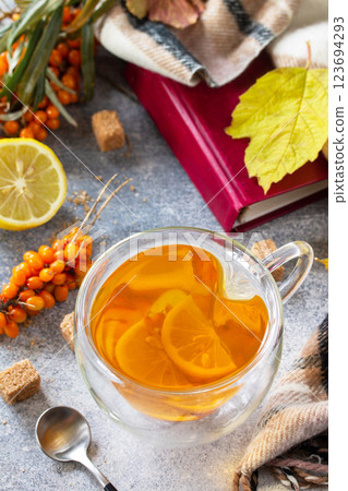 Healthy autumn vitamin drink. Hot Sea buckthorn tea with lemon with fresh sea buckthorn berries on a stone countertop. Healthy autumn vitamin drink. Hot Sea buckthorn tea with lemon with fresh sea buckthorn berries on a stone countertop. 123694293